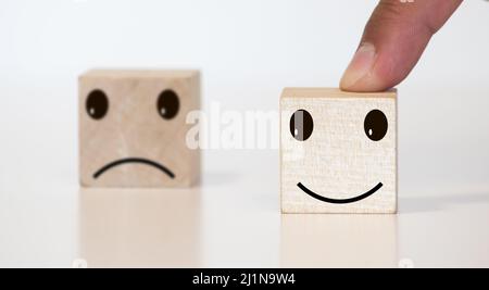 Homme d'affaires choisit un sourire émoticône icônes face heureux symbole sur bloc de bois , Services et le concept d'enquête de satisfaction client Banque D'Images