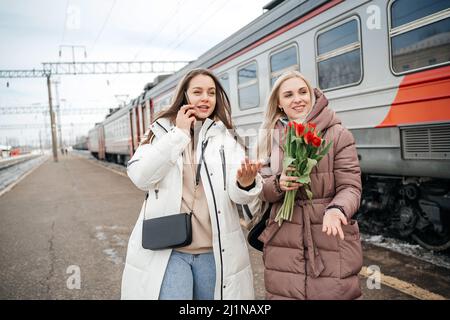 Deux amies rencontrent un ami à la gare Banque D'Images