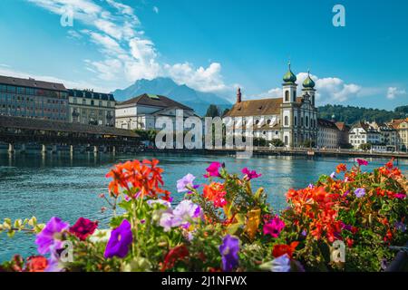 Célèbre destination touristique et touristique à Lucerne. Église de Jesuitenkirche et rivière Reuss. Vue sur le front de mer avec pont fleuri en bois de la chapelle, Lucerne, Banque D'Images