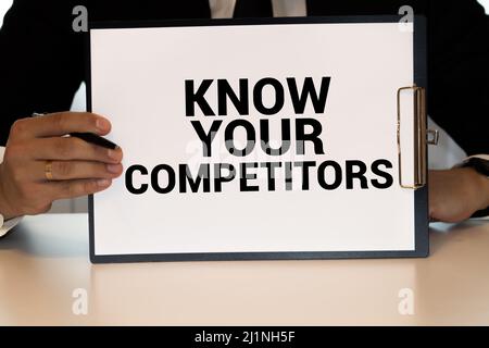 Gros plan sur businessman holding une carte avec texte CONNAISSEZ VOS CONCURRENTS, concept d'entreprise image avec arrière-plan flou et vintage tone Banque D'Images