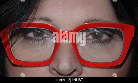 Gros plan d'une femme aux yeux bruns portant des lunettes rouges brillantes Banque D'Images