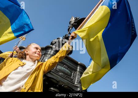 Londres, Royaume-Uni, 26th mars 2022. Des milliers de personnes se joignent à un stand avec l'Ukraine mars et vigile dans le centre de Londres pour protester contre l'invasion russe. Une jeune femme hante un drapeau ukrainien sous le monument de Piccadilly Circus. Banque D'Images