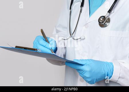 Médecin remplissant un rapport médical sur fond gris Banque D'Images