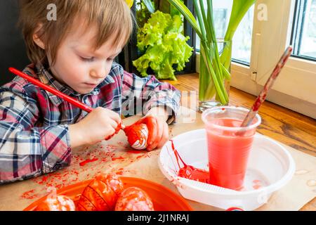 L'enfant se préparant pour Pâques. Peindre les œufs. Œuf de peinture rouge. Banque D'Images