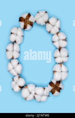 Lettre O faite de fleurs de coton et isolée sur fond bleu Uni. Concept de l'alphabet floral. Une lettre de l'ensemble de police de coton facile à empiler. Banque D'Images