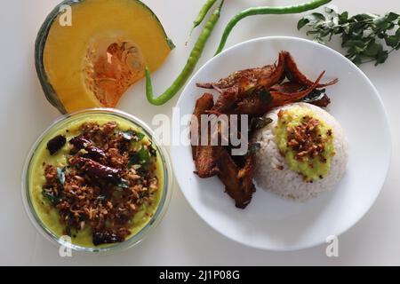 Repas au Kerala avec riz rouge mata bouilli, curry de citrouille à base de noix de coco et frites anchois. Prise de vue sur fond blanc Banque D'Images