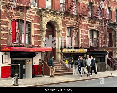 Les gens marchent à côté de petits immeubles d'appartements qui font partie du charme de Greenwich Village. West 12th Street, sortie 6th Avenue, New York City. Banque D'Images