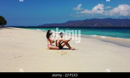 Un couple caucasien assis sur la plage et appréciant la vue panoramique à Gili Meno, Lombok, Indonésie Banque D'Images