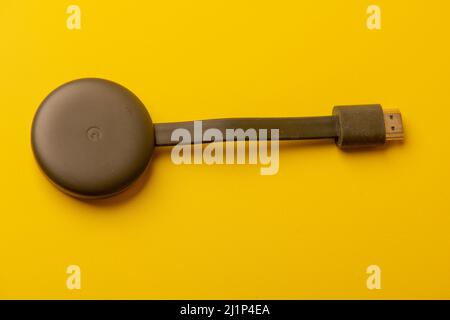 Google Chromecast anthracite avec logo sur fond jaune. Banque D'Images