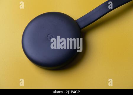 Google Chromecast anthracite avec logo sur fond jaune. Banque D'Images