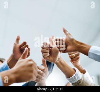 Nous adorons ce que vous faites. Photo d'un groupe d'hommes d'affaires méconnus montrant les pouces dans un bureau. Banque D'Images