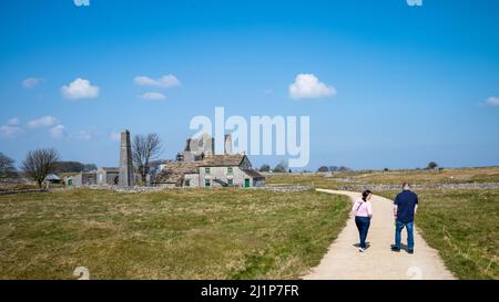 Un couple marche sur le chemin pour visiter la mine de Magpie en ruines, une ancienne mine de plomb près du village de Sheldon dans le parc national de Peak District Banque D'Images