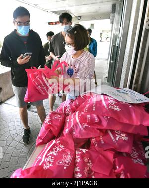 Hong Kong, Chine. 27th mars 2022. Un personnel distribue des fournitures de lutte contre les épidémies aux résidents de Hong Kong, dans le sud de la Chine, le 27 mars 2022. Dimanche, Hong Kong a enregistré 3 555 nouveaux cas de COVID-19 par des tests d'acide nucléique, et 4 482 autres cas positifs par des tests d'antigène rapides auto-déclarés, ont montré des données officielles. Crédit : Lo Ping Fai/Xinhua/Alamy Live News Banque D'Images