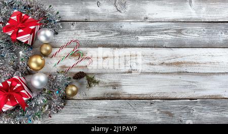 Boules traditionnelles d'argent et d'or, cannes de bonbons, présente tous entourés de tinsel sur un fond de bois blanc pour la mer de Noël ou de vacances du nouvel an Banque D'Images