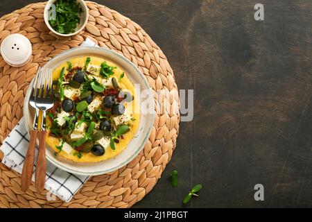 Œufs brouillés. Des œufs brouillés légers, doux et Buttery avec du fromage feta, des tomates séchées et des olives noires sur l'assiette sur le vieux bois sombre rustique Banque D'Images