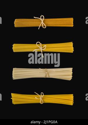 Variété de spaghetti liés à la corde de jute, isolés sur une surface noire. Cette image peut être utilisée horizontalement ou verticalement. Banque D'Images