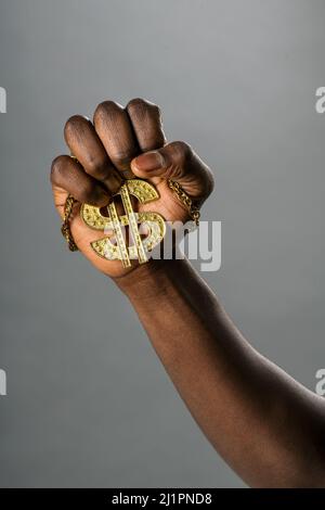 Rognez un homme afro-américain méconnaissable portant un collier doré avec un symbole dollar sur fond gris Banque D'Images