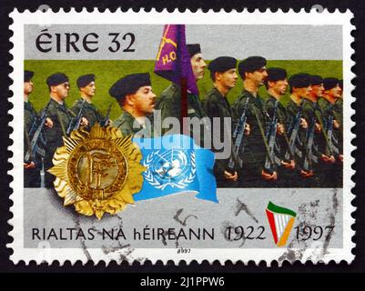 IRLANDE - VERS 1997 : un timbre imprimé en Irlande présente les Forces de défense irlandaises, les insignes et le drapeau de l'ONU, vers 1997 Banque D'Images