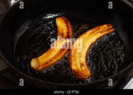 Bananes frites dans une poêle. Bananes crues bouillies dans l'huile. Banque D'Images