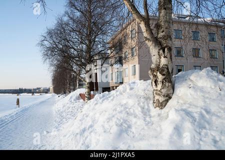 Une scène hivernale typique d'une rue enneigée sur la rive de la rivière Kemijoki gelée, Rovaniemi, Finlande Banque D'Images