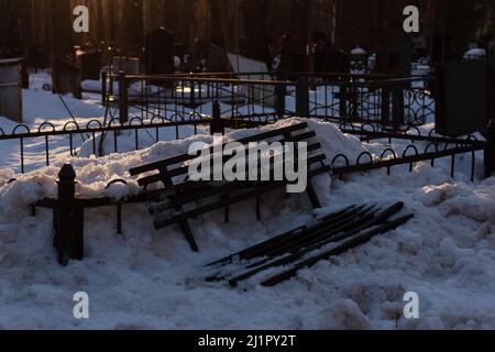 Une photo d'un banc brisé dans un cimetière dans la neige à Moscou Banque D'Images