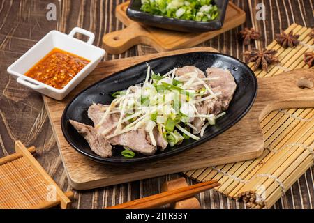 viande de porc dans un plat avec sauce chili isolée sur panneau de bois vue latérale sur la table nourriture de taiwan Banque D'Images