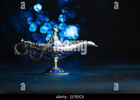 Lampe d'Aladdin antique, incrustée de pierres précieuses sur fond bleu avec des lumières. Contes arabes, fantasmes. Symbole de réalisation de souhaits. Il n'y en a pas Banque D'Images