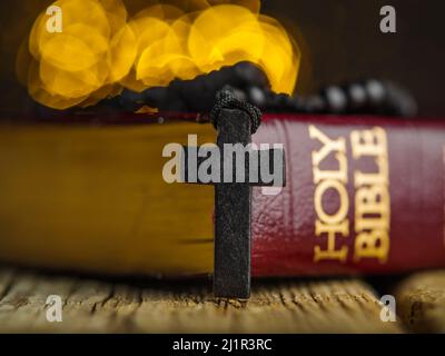 Prise de vue macro. Livre rouge de la sainte bible sur une table en bois et une croix catholique. Symboles du catholicisme, de la foi, de la spiritualité. Arrière-plan jaune. Il y a un Banque D'Images