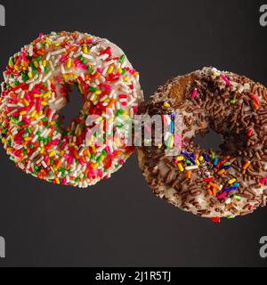 Deux beignes appétissantes en vol libre sur fond gris. Minimalisme. Il n'y a aucune personne dans la photo. Anniversaire, petit déjeuner sucré, calories délicieuses Banque D'Images