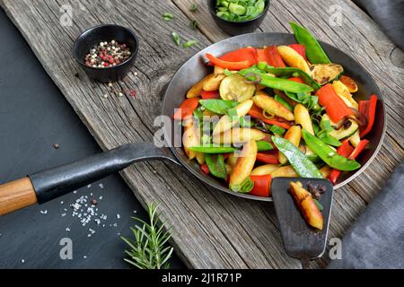 Boulettes de pommes de terre vegan rôties en forme de doigts avec légumes frais dans une poêle à frire en fer Banque D'Images