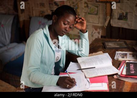 Prisca, 23 ans, maintenant étudiant, faisant du travail d'université à la maison. Elle est orpheline du sida et chef de son foyer de trois enfants plus jeunes, Meru, Kenya. Banque D'Images