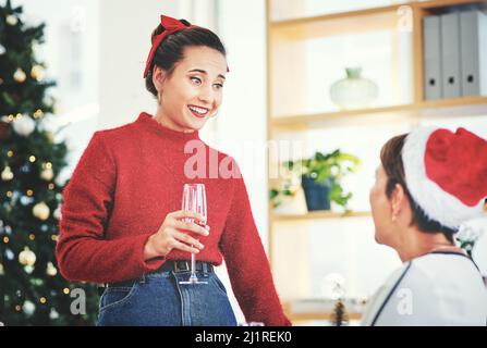 Nous nous sentons joyeux et festifs aujourd'hui. Photo de deux jeunes femmes séduisantes buvant du champagne et célébrant ensemble lors de leur fête de Noël au bureau. Banque D'Images