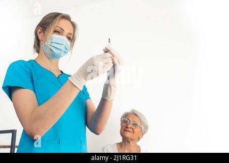 Une jeune infirmière prépare une injection pour une patiente âgée de la retraité. . Photo de haute qualité Banque D'Images