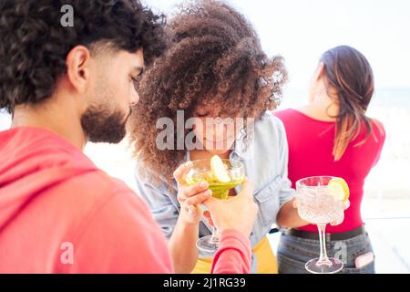 Les jeunes amis multiraciaux applaudient en s'amusant ensemble en dégustant des cocktails sur le toit. Concept de style de vie de communauté sociale Banque D'Images