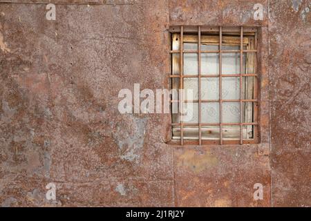 Authentique fond marron naturel avec teintes rouges. Une prison en métal sur la fenêtre d'une vieille maison qui ressemble à une prison gainée de merde en métal Banque D'Images