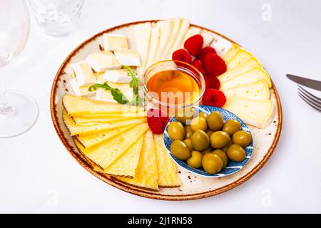Différents types de fromage, miel, framboises et olives sur bois Banque D'Images