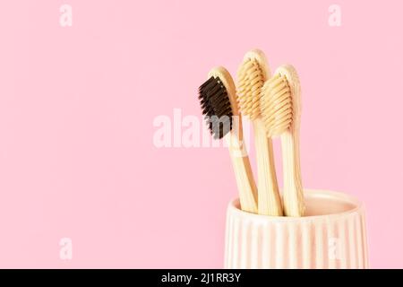 Ensemble de brosses à dents en bambou naturel dans un verre en céramique sur fond rose. Concept écologique, sans gaspillage. Espace de copie pour le texte, sélection Banque D'Images