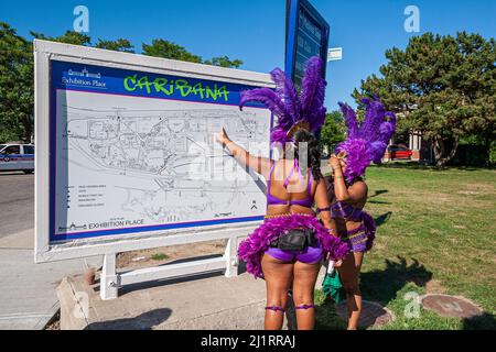 Toronto, Ontario - Festival Caribana participantes en costumes colorés à la recherche d'indications sur la carte de la parade Banque D'Images