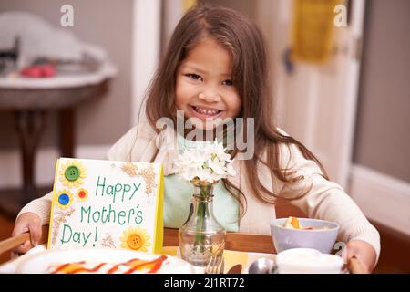 Un cadeau pour maman. Une petite fille qui apporte son petit déjeuner de mère au lit le jour de la fête des mères. Banque D'Images