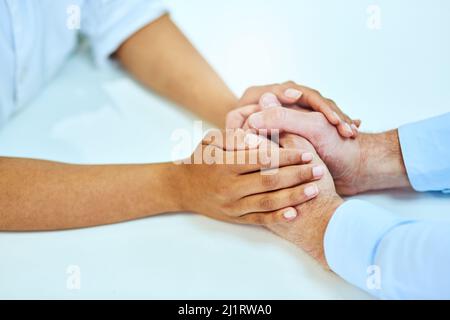 Je suis ici pour vous. Prise de vue en grand angle de deux personnes méconnaissables tenant les mains confortablement. Banque D'Images