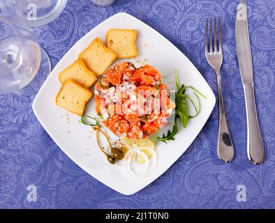 Tartare de saumon à l'avocat servi avec des toasts, des verts, du citron et des câpres Banque D'Images