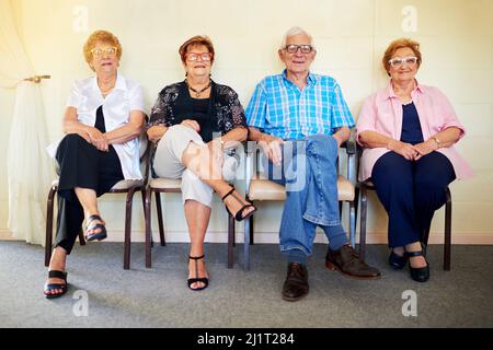 En attente de nos petits-enfants. Photo d'un groupe de personnes âgées gaies souriant et posant pour la caméra à l'intérieur d'un bâtiment. Banque D'Images