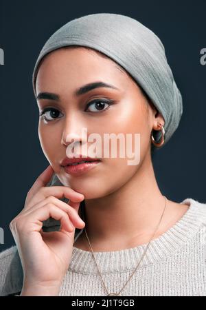 Je porte mon hijab fièrement. Photo courte d'une jeune femme attrayante portant un foulard et debout seule sur un fond noir dans le studio. Banque D'Images