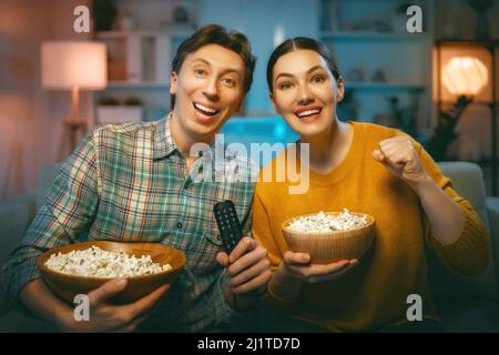 Bonne famille regardant le projecteur, la télévision, des films avec pop-corn le soir à la maison. Couple passant du temps ensemble. Banque D'Images