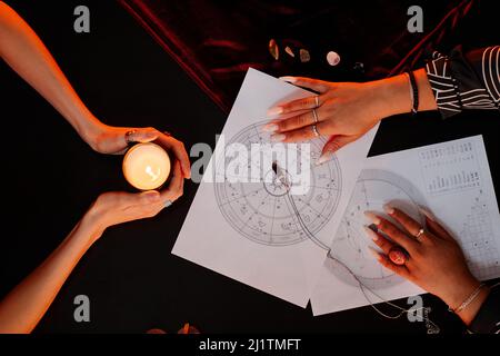 Vue de dessus de la femme de la chance teller lisant le tableau d'astrologie pour la jeune femme visitant à la séance spirituelle Banque D'Images