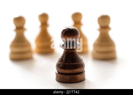 Pion d'échecs noir parmi les blancs. Notion de racisme et de discrimination. Banque D'Images