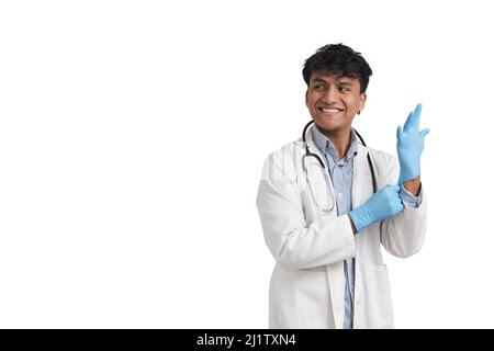 Jeune péruvien homme médecin souriant et portant des gants bleus, isolé. Banque D'Images