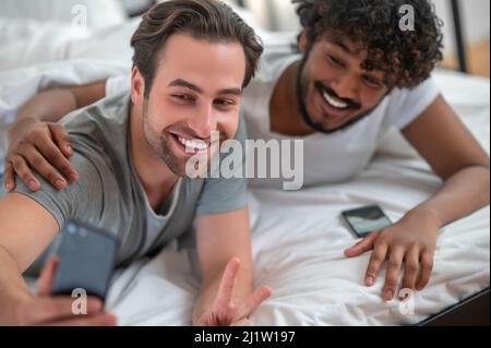 Joyeux jeune couple gay biracial prenant des selfies Banque D'Images