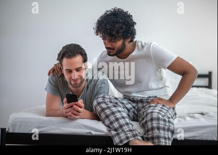 Couple gay concentré regardant des selfies sur le téléphone portable Banque D'Images