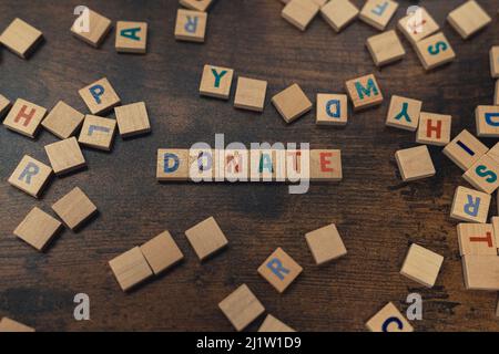DONNER - un mot mis avec des lettres de l'alphabet sur le concept de table de charité en bois brun. Photo de haute qualité Banque D'Images